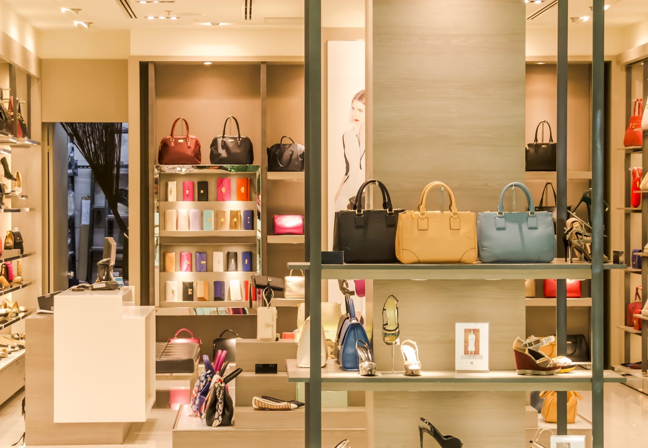 gallery-05 Chic boutique with a variety of handbags and shoes elegantly displayed on shelves.