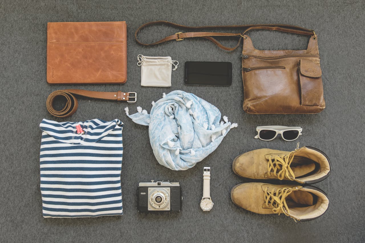 gallery-01 Vintage travel essentials flat lay with leather bags, shoes, camera, and clothing.